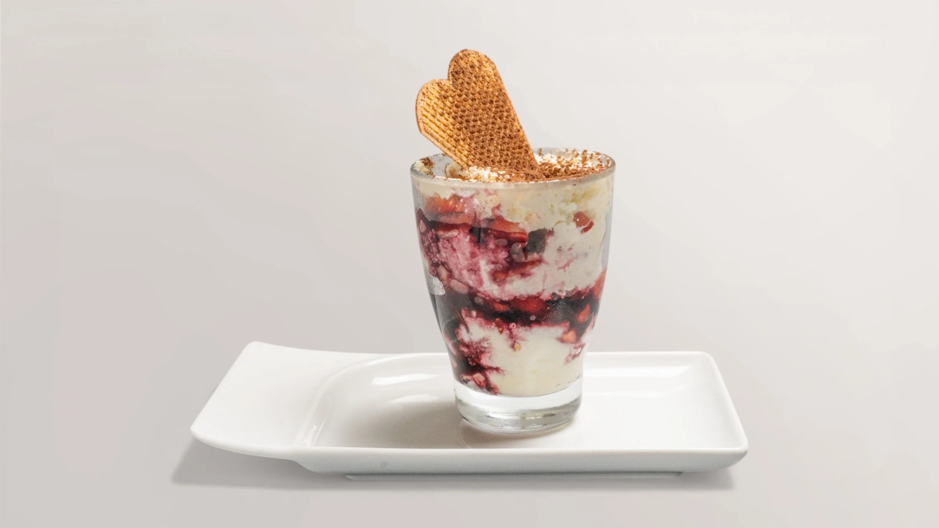 Erdbeer-Tiramisu im Glas mit Waffelherz und Kakao bestäubt