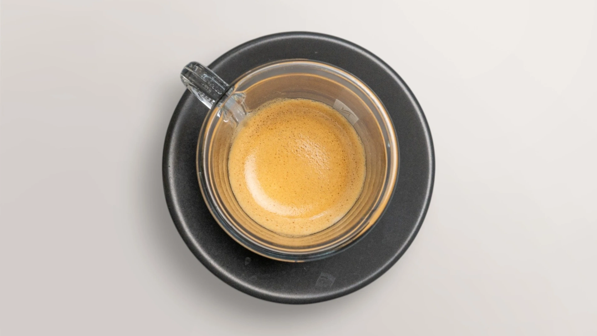 Frisch gebrühter Espresso in einer Glastasse auf schwarzem Teller
