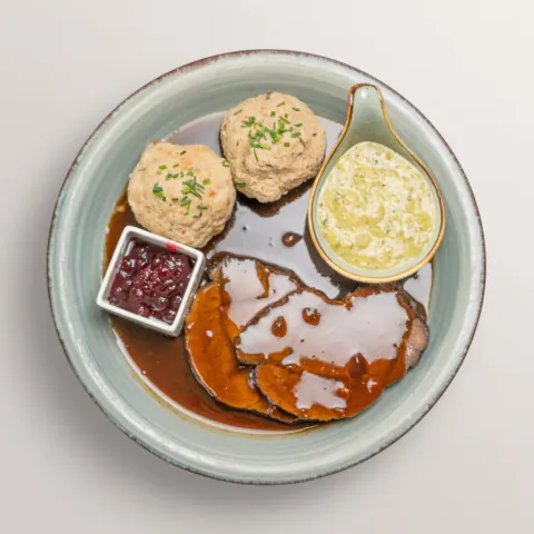 Roast venison with bread dumplings, lingonberries and sauce