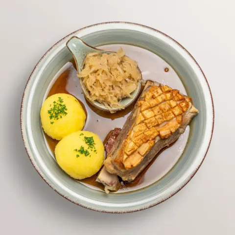 Franconian roast pork shoulder with crisp crackling, potato dumplings and sauerkraut